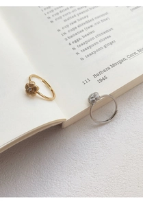 Detail view of gold and silver flower rings with cubic zirconia on book pages