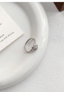 Detailed view of an S999 silver hollow flower ring with a sparkling zircon center