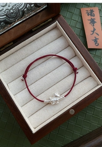 Detail of red hand-woven cord bracelet with S999 silver horse charm in a vintage gift box