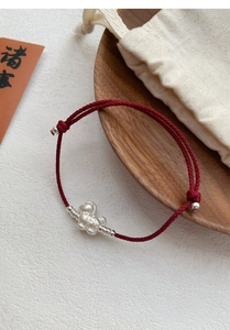 Macro detail of red woven rope bracelet with matte silver horse charm and adjustable knot