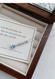 Detailed view of silver teardrop pendant with blue gemstone in a wooden gift box