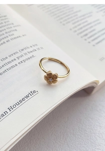 Detailed view of an 18K gold flower ring with a zircon center set on an open book