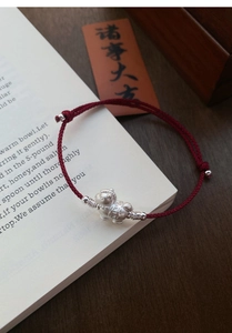 Detail of red braided zodiac goat bracelet with S999 silver pendant and lucky coin patterns
