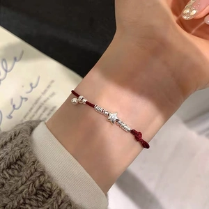 Handcrafted red woven string bracelet with S925 silver lucky star and bell on woman's wrist