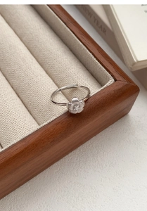 Detailed view of S999 sterling silver flower ring with zircon center in wood jewelry box