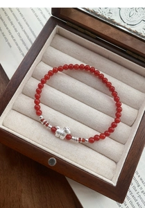 Dettaglio ravvicinato del bracciale con perline di agata rossa e ciondolo a forma di agnello