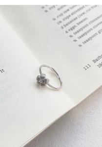 Macro shot of brushed silver flower ring with zircon center on an open book