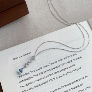 S999 silver necklace featuring a blue teardrop zircon pendant on an elegant book background