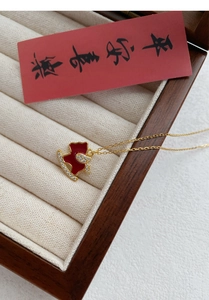 Détail du pendentif pégase en émail rouge et zircons dans un coffret à bijoux en bois vintage
