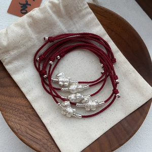Handcrafted red woven S999 silver horse zodiac bracelet on a rustic linen pouch display