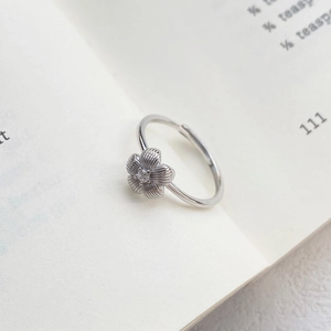Vintage S999 sterling silver brushed flower ring with zircon on a book page
