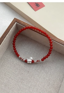 Dettaglio del ciondolo in argento S999 e perle di agata rossa su bracciale di lusso