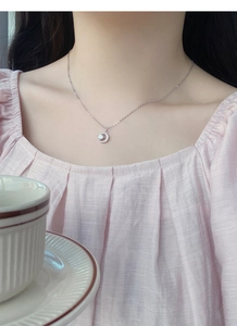 Dettaglio della collana a mezzaluna in argento con zirconi lucenti sulla clavicola