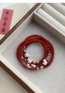 Dettaglio del bracciale multistrato in agata rossa con ciondoli Pixiu in argento e cofanetto