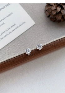 Close-up of S999 silver heart stud earrings with sparkling crystals on a rustic wood tray