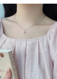 Dettaglio della collana a mezzaluna in argento S999 con zirconi indossata da una modella