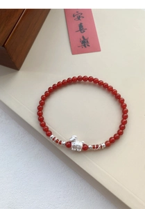 Dettaglio ciondolo cavallo in argento S999 su bracciale di agata rossa con carta