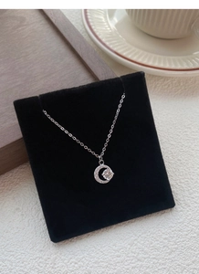 Dettaglio della collana a mezzaluna in argento S999 con zircone su espositore nero
