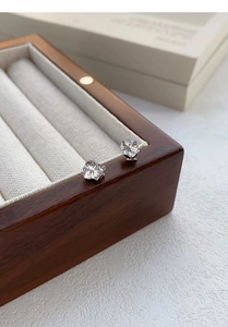 Close-up of S999 sterling silver heart-shaped stud earrings on wooden jewelry box