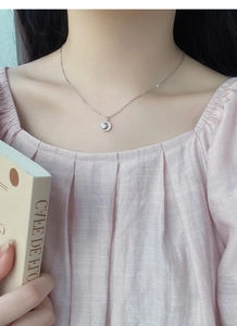 Dettaglio della collana con ciondolo a mezzaluna e zirconi scintillanti indossata da modella