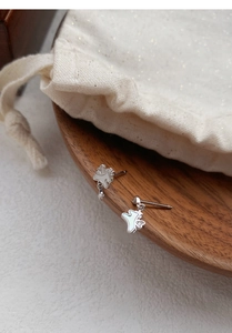 Détail de boucles d'oreilles licorne en argent avec nacre blanche sur bois brun