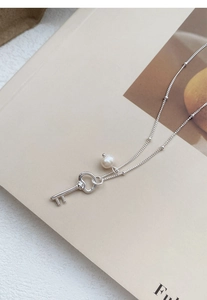 Macro shot of S925 silver key pendant with freshwater pearl on vintage book