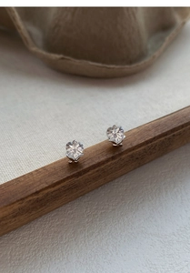 Macro shot of S999 silver heart stud earrings with faceted crystals on a wooden base