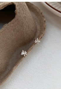 Dettaglio degli orecchini a lobo orchidea in argento S999 con zircone su sfondo ruvido