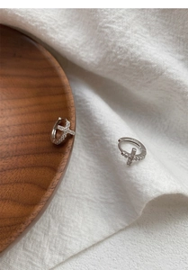 Macro shot of S925 sterling silver cross earrings with crystals on a wooden tray