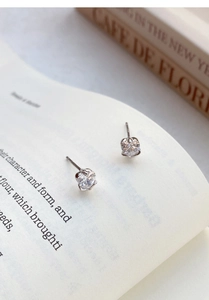 Macro detail of S999 sterling silver rose heart earrings on white book pages