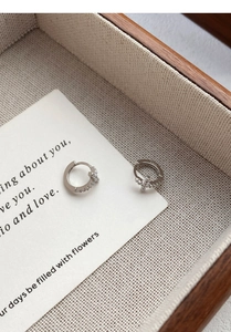 Detail shot of silver S925 cross hoop earrings with inlaid cubic zirconia on linen