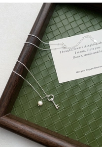 Detailed macro view of S925 sterling silver stamp on key pendant necklace with pearl