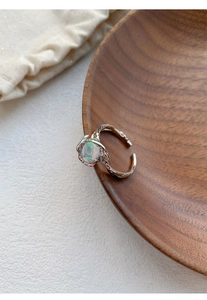 Macro detail of irregular lava texture S925 silver ring with opal stone on wood