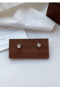 Detail of S925 silver heart stud earrings with claw-set clear zircon on a wood stand