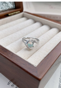 Close-up of irregular lava silver ring with iridescent opal stone in a wooden box