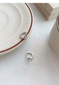 Macro detail of S999 sterling silver hoop earrings with sparkling cross charms on ceramic