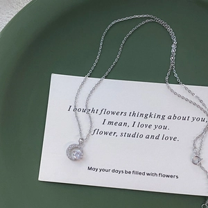 Collana in argento S999 con ciondolo a mezzaluna e zirconi su un vassoio verde scuro