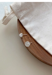 Detail shot of asymmetric S999 silver earrings featuring rose and cartoon face designs