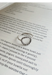 Détail d'une bague torsadée en argent sterling S925 posée sur une page de livre ancien