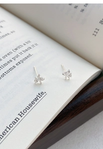 Dettaglio orecchini a lobo farfalla orchidea in argento S999 con zirconi su un libro