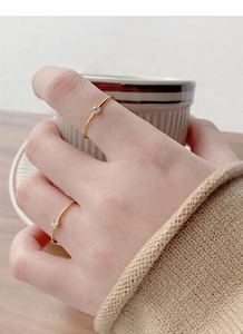 Close-up of minimalist thin gold rings with single tiny zircons worn on hand