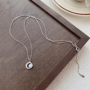 Collana luna in argento S999 con zirconi scintillanti su vassoio in legno scuro