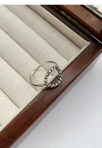 Gros plan d'une bague en argent S925 tressée creuse présentée dans un écrin en bois