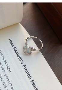 Detailed shot of S925 silver irregular lava texture ring with oval opal on book pages
