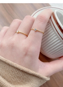 Close-up of two minimalist gold S925 silver rings with single diamonds on a finger