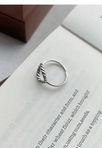 Détail d'une bague en argent S925 avec motif torsadé et anneau ouvert ajustable