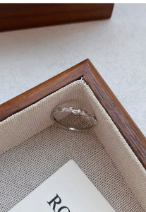 Macro shot of S999 silver wheat ear ring with zircon inlay on a textured fabric