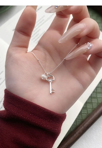 Close-up of S925 sterling silver key pendant with elegant pearl on a fine chain