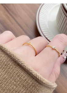Detail of two minimalist gold thin rings with round zircon stones worn on fingers