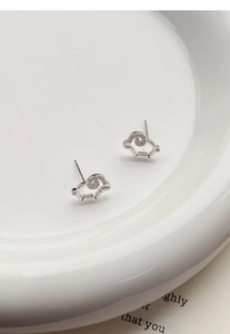 Dettaglio orecchini a pecora in argento S925 con zirconi su un piatto di ceramica bianca